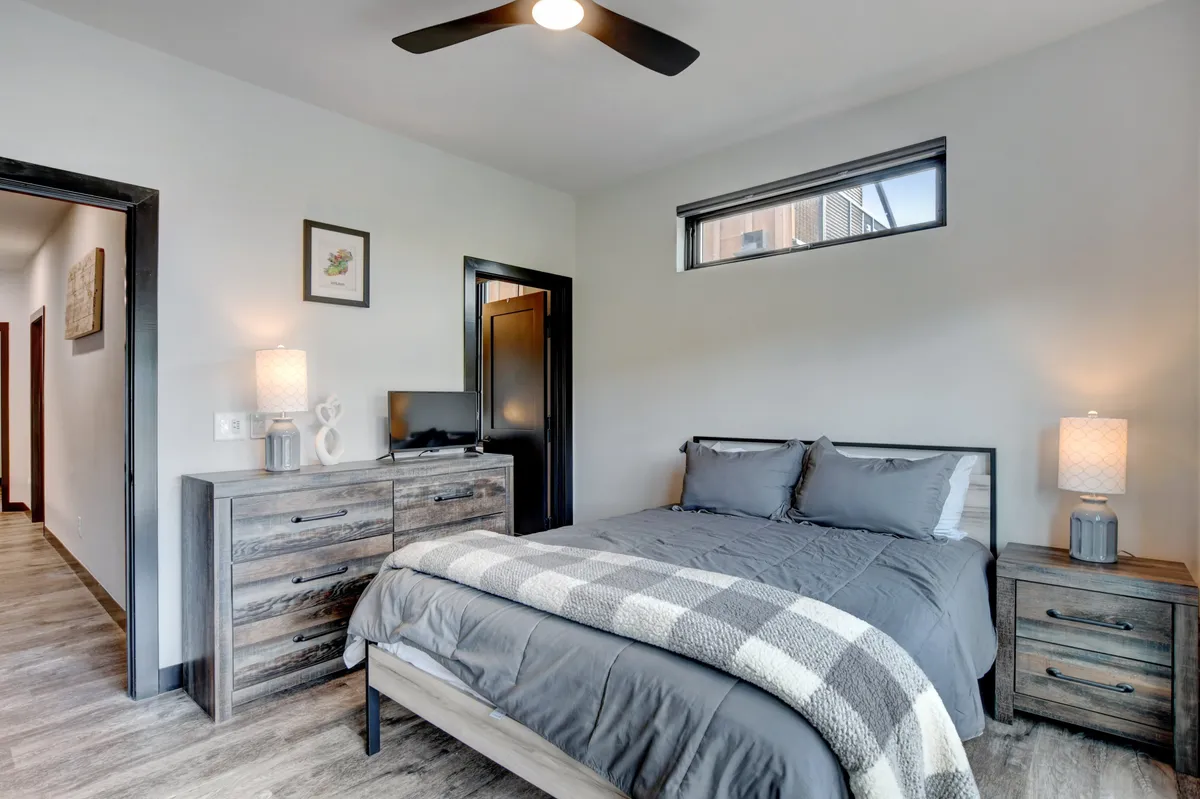 A serene bedroom featuring a comfortable bed with premium bedding, two nightstands, a dresser, and a window that lets in gentle natural light. The space feels tranquil and perfectly suited for restful nights.