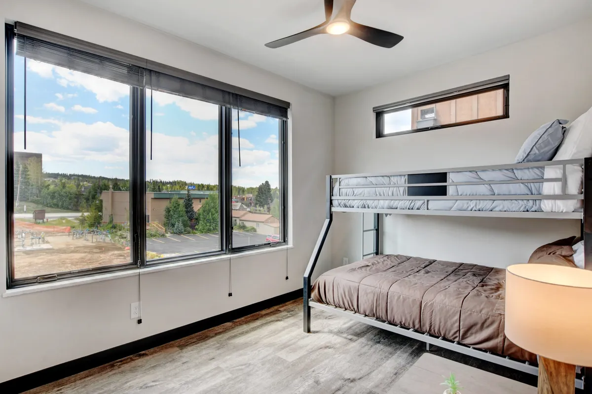 This image shows a cozy bunk bed setup adjacent to large windows looking out at nature, allowing for natural light and views of the outdoors from inside. The space feels comfortable and inviting, ideal for relaxing after exploring with your pet.