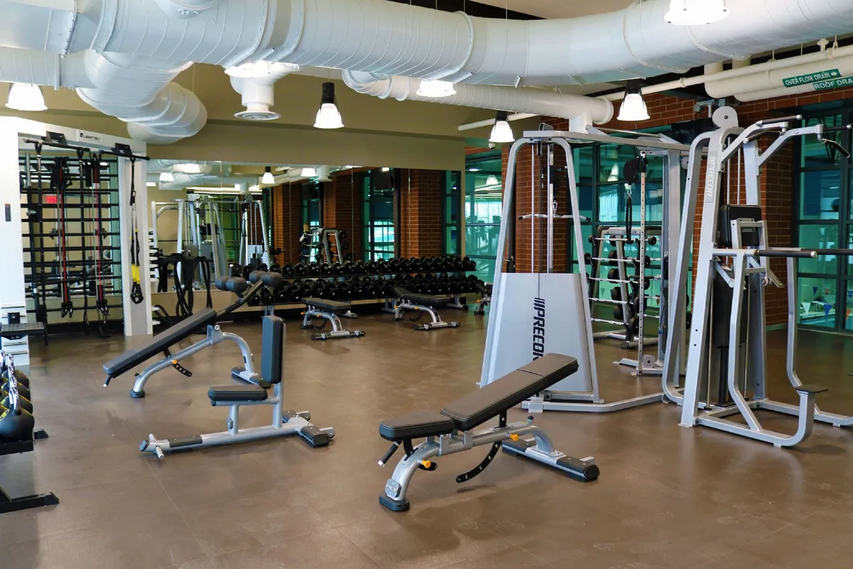 A modern fitness room with weight benches, dumbbells, and strength training machines, inviting guests to embark on workouts or join group fitness classes in a motivating setting.